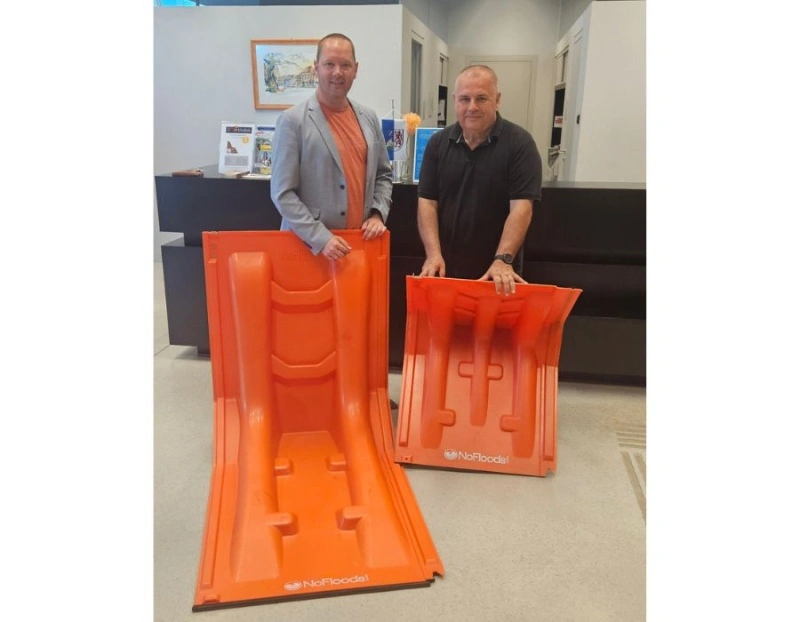 Hochwasserschutz: Zwei Männer präsentieren mobile Barrieren in orange
