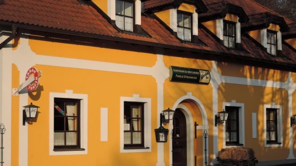 Gelbes Wirtshaus von au&szlig;en mit Trafik Schild an der Hausecke
